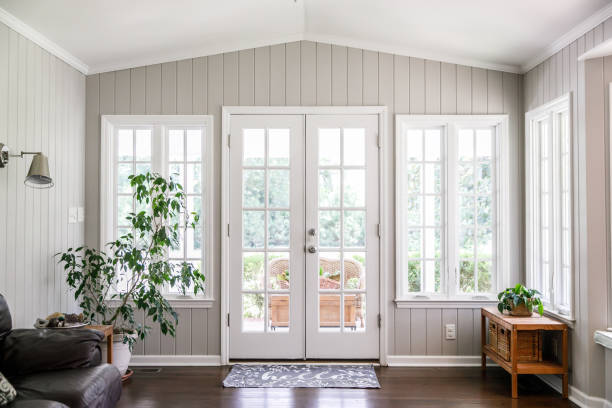 istockphoto-1178826957-612x612 Large and open living room den sun room with windows on two sides and lots of natural light flowing in. There is a window seat on one side and a leather couch and plant on the other.